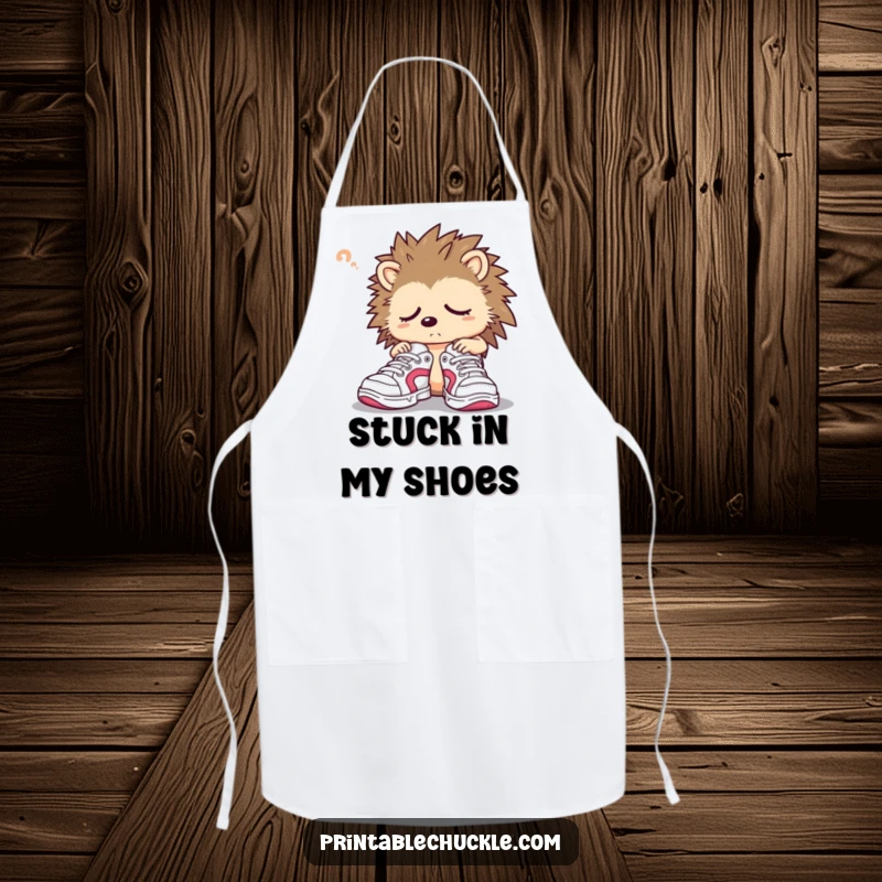 Funny hedgehog apron featuring a sleepy character confusedly trying on oversized sneakers, perfect for cooking.