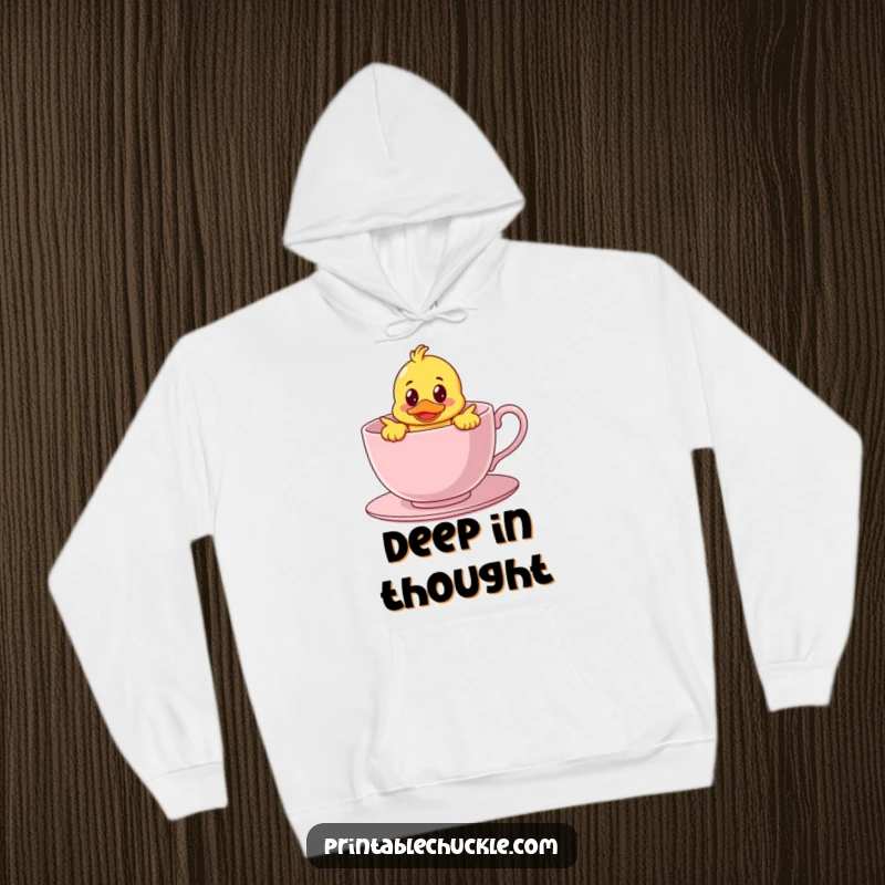 Funny hoodie showing a bewildered rubber duck character hilariously stuck inside a giant teacup, perfect for cozy, whimsical humor.